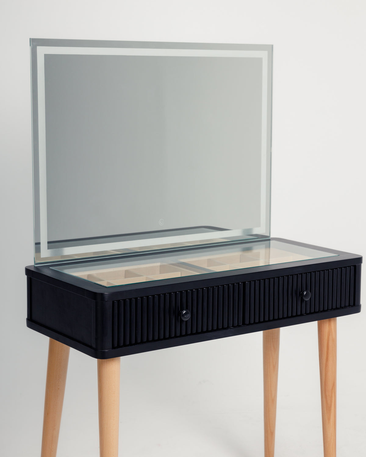 A sleek black dresser features a large, rectangular mirror with a minimalist frame, and a textured front with two drawers, supported by light wooden legs.