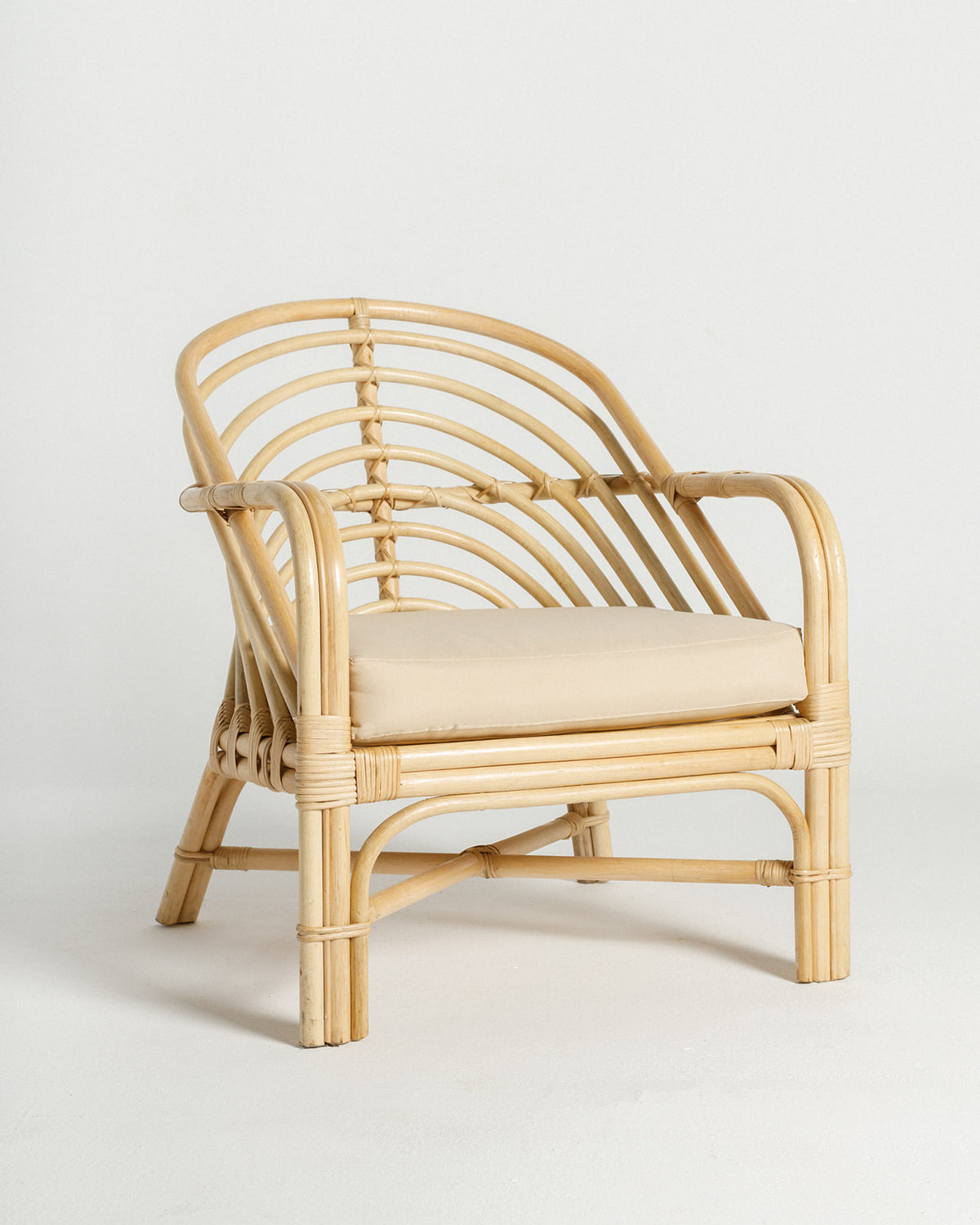 A stylish bamboo chair featuring a curved backrest and armrests, complemented by a soft beige cushion.
