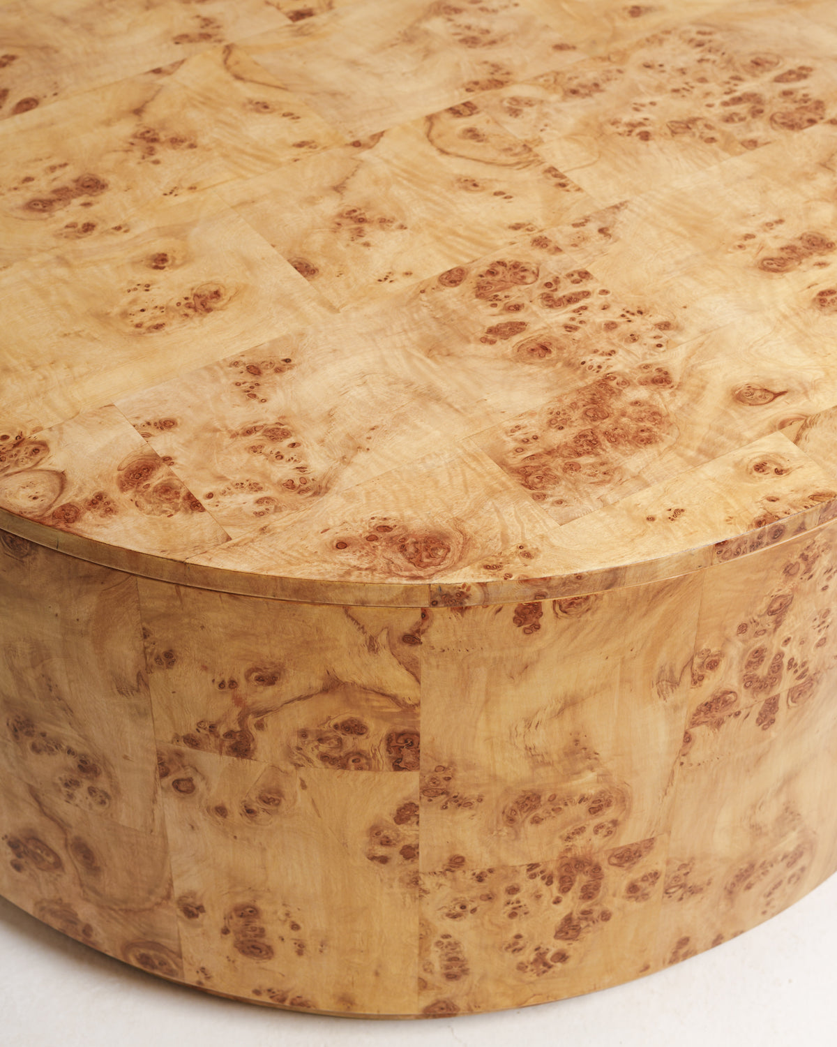 Close-up view of a burlwood round coffee table showcasing its unique, natural grain patterns and warm wood tones. The table features a smooth, rounded surface and a sturdy, seamless design, perfect for enhancing any living space.