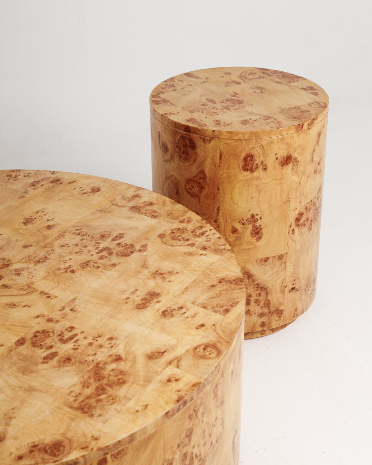 Two round side tables made of burlwood are displayed against a white background. The tables feature a natural wood grain pattern with warm tones, showcasing their elegant design and smooth surfaces, perfect for decorative purposes.