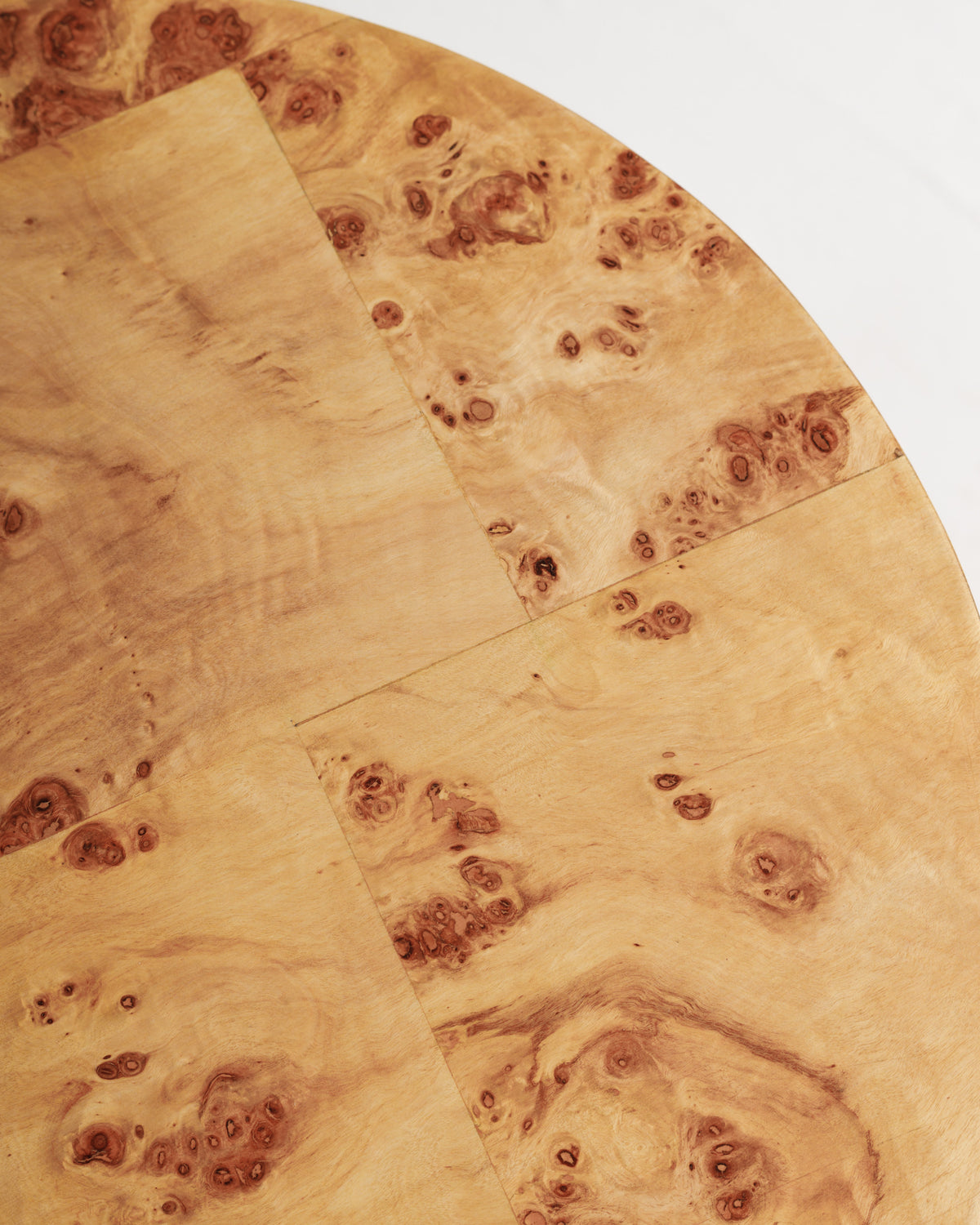 Close-up view of a round burlwood tabletop featuring a smooth, polished surface with intricate patterns and natural grain variations. The warm tones and unique textures create an elegant aesthetic, perfect for enhancing any interior space.
