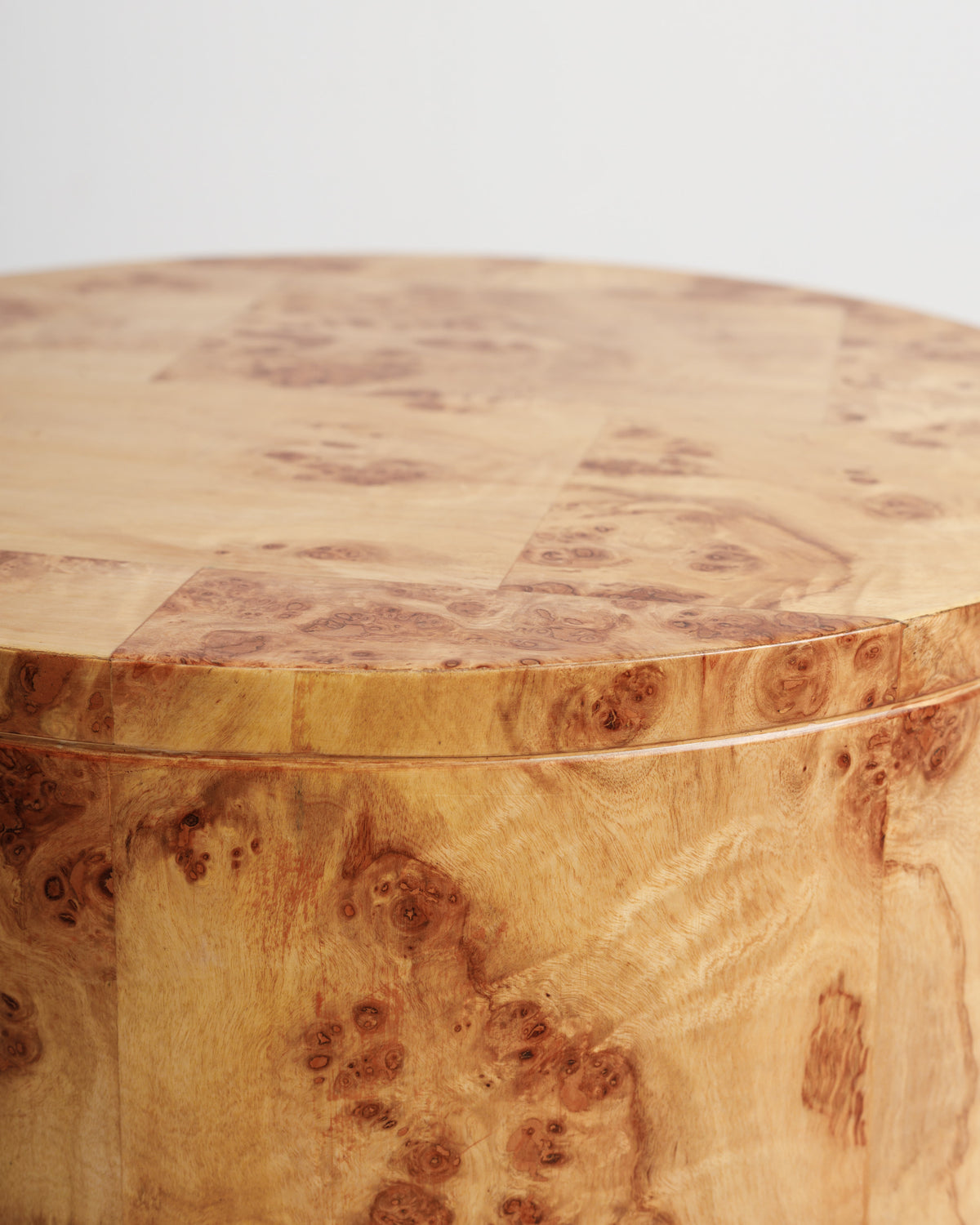 Close-up view of a round side table featuring a beautifully patterned burlwood surface. The table showcases intricate wood grain details and a smooth, polished finish, making it an elegant addition to any living space.