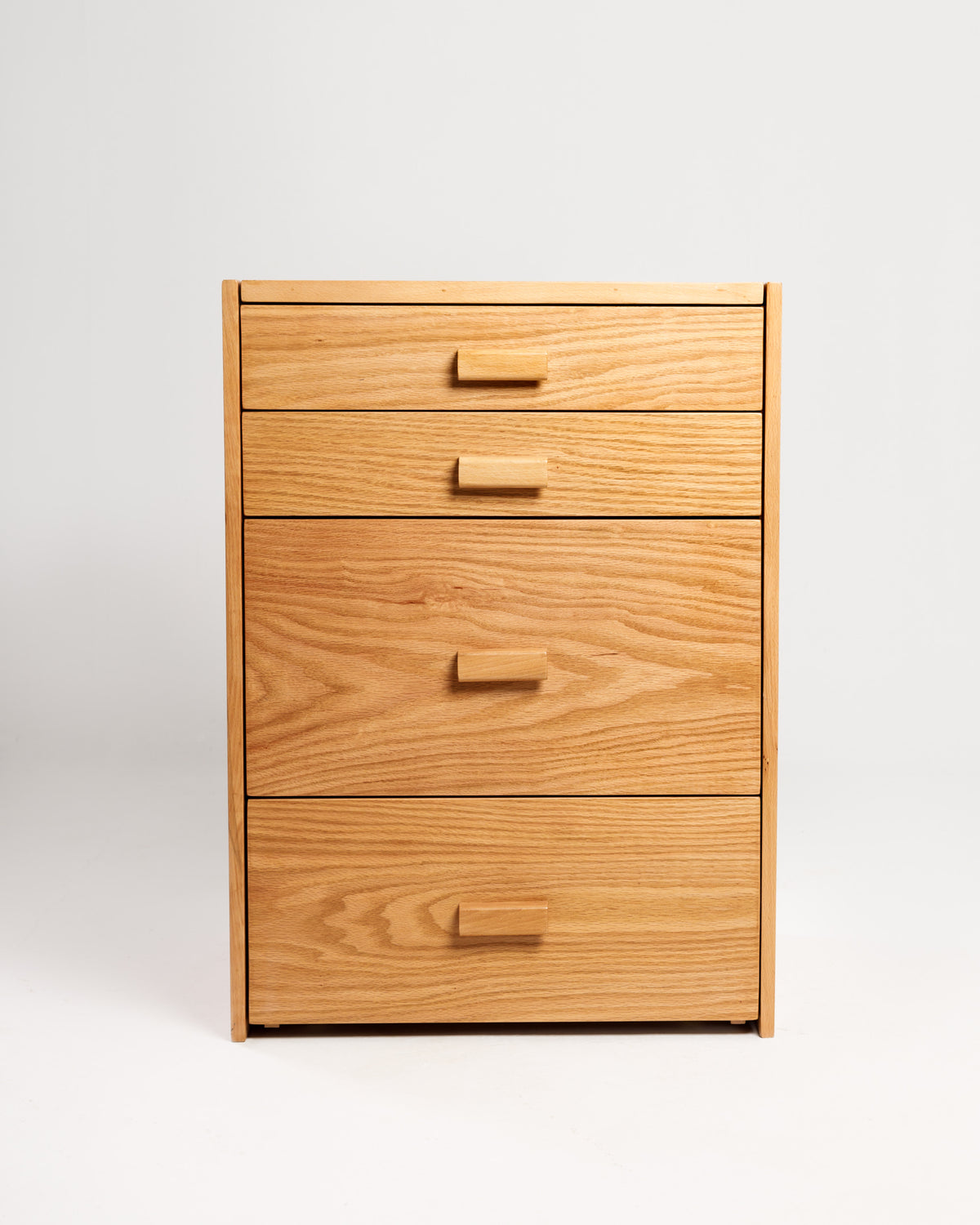A compact wooden dresser with four drawers is displayed against a plain white background. The dresser features a natural wood finish and simple wooden handles, making it a stylish and functional storage solution for any space.