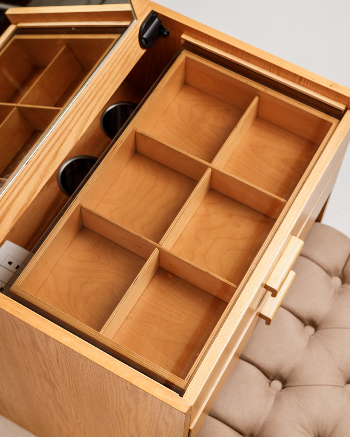 An overhead view of a spacious wooden drawer featuring multiple compartments for organization. The drawer is part of a stylish vanity with a mirror, designed for storing makeup and jewelry efficiently.