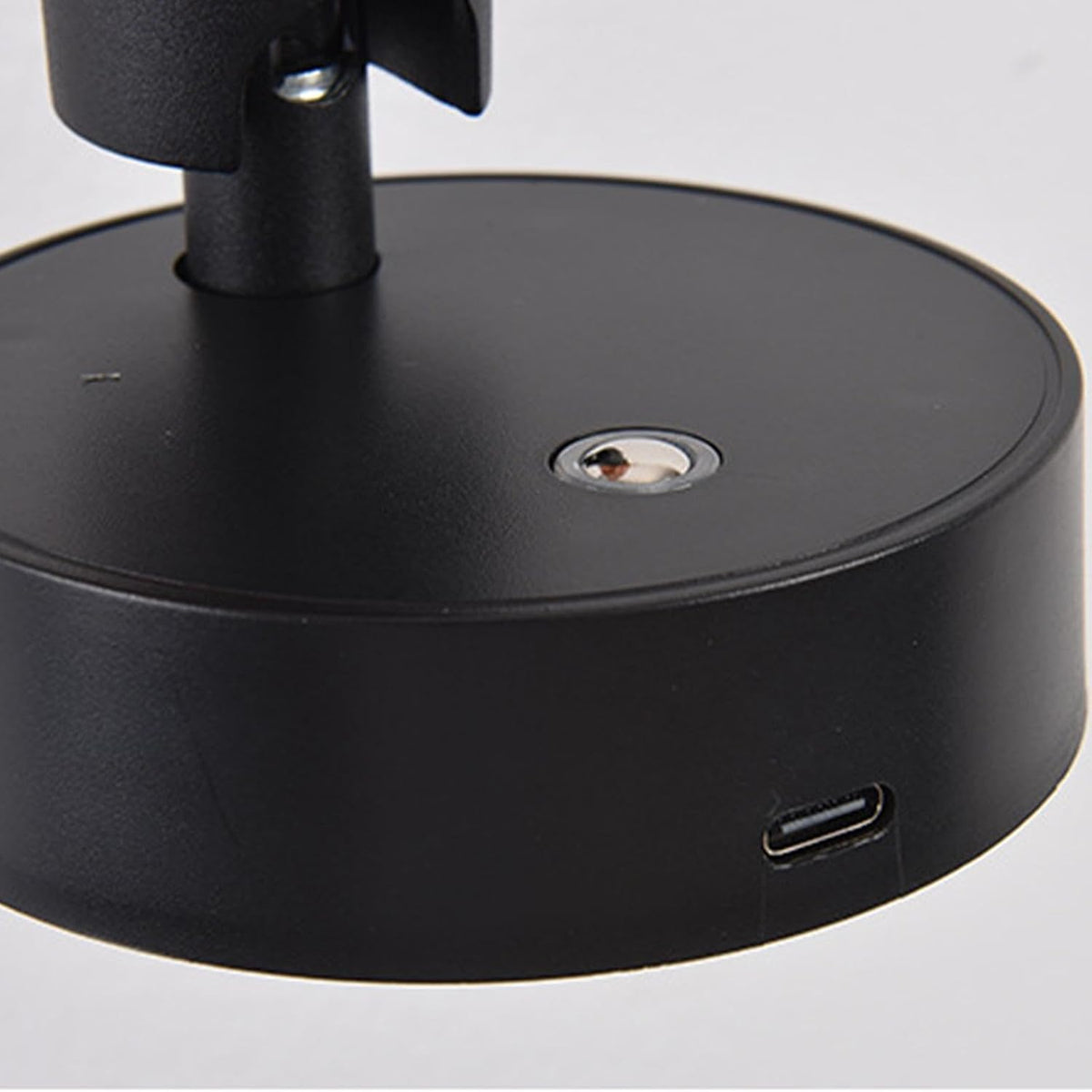 Close-up view of a sleek black base of a modern LED wall lamp, featuring a magnetic attachment and a Type-C charging port on one side. The minimalist design highlights its contemporary aesthetic, suitable for various interior settings.
