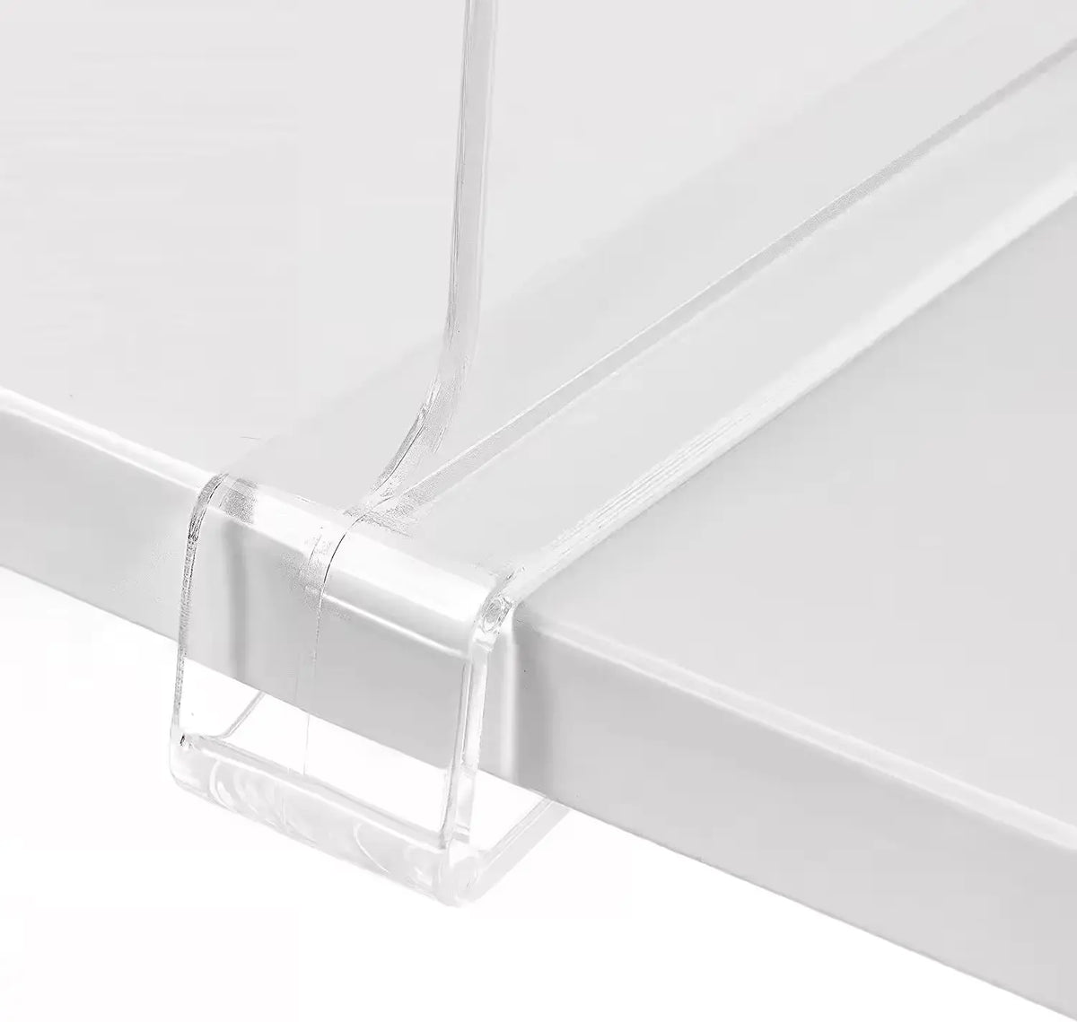 Clear acrylic shelf divider resting on a white shelf, showcasing its sleek design and sturdy construction. The divider features a seamless edge that allows for easy organization and separation of items on the shelf.